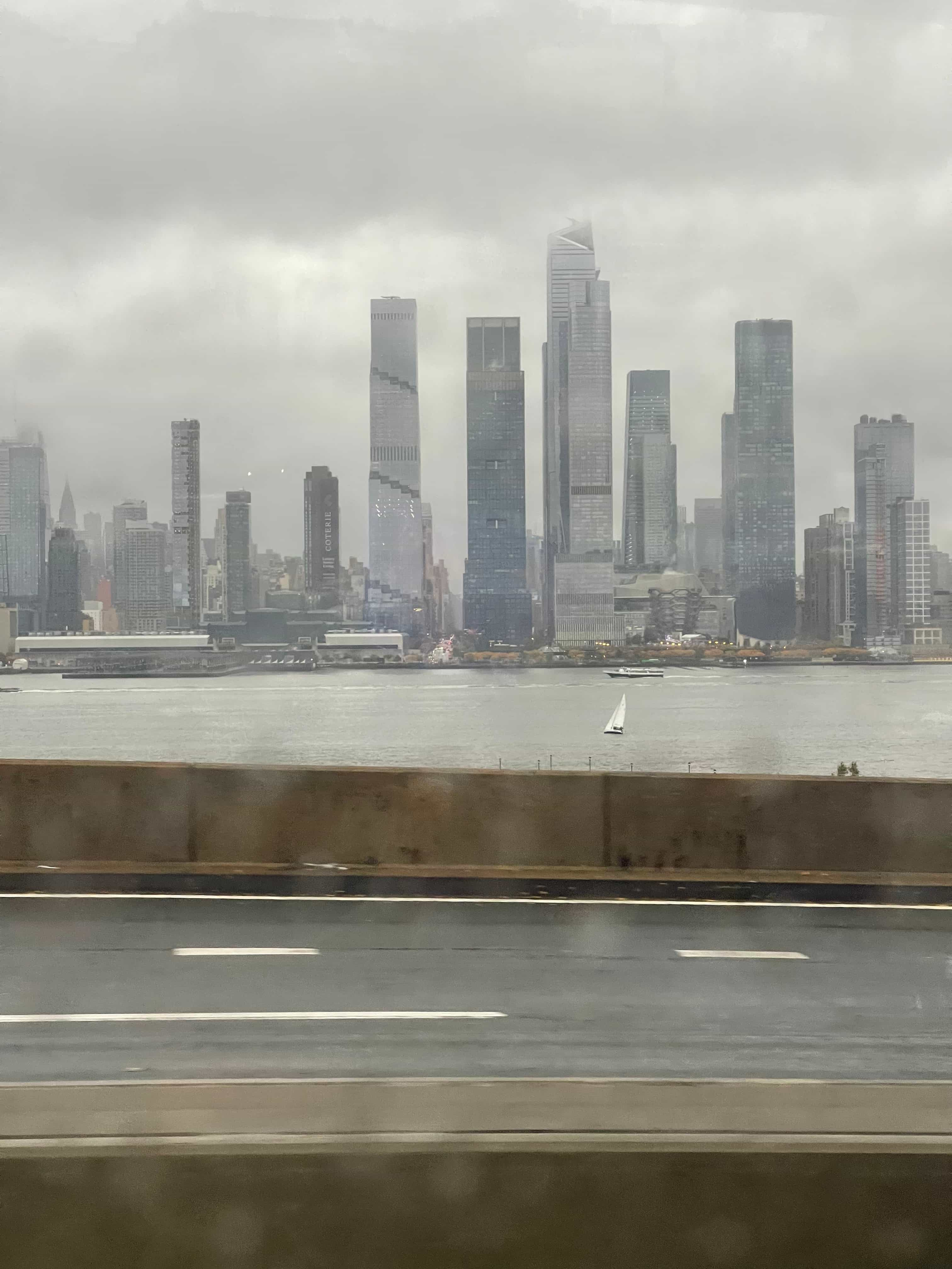 a view of skycrapers across a river taken from a highway on a gloomy day