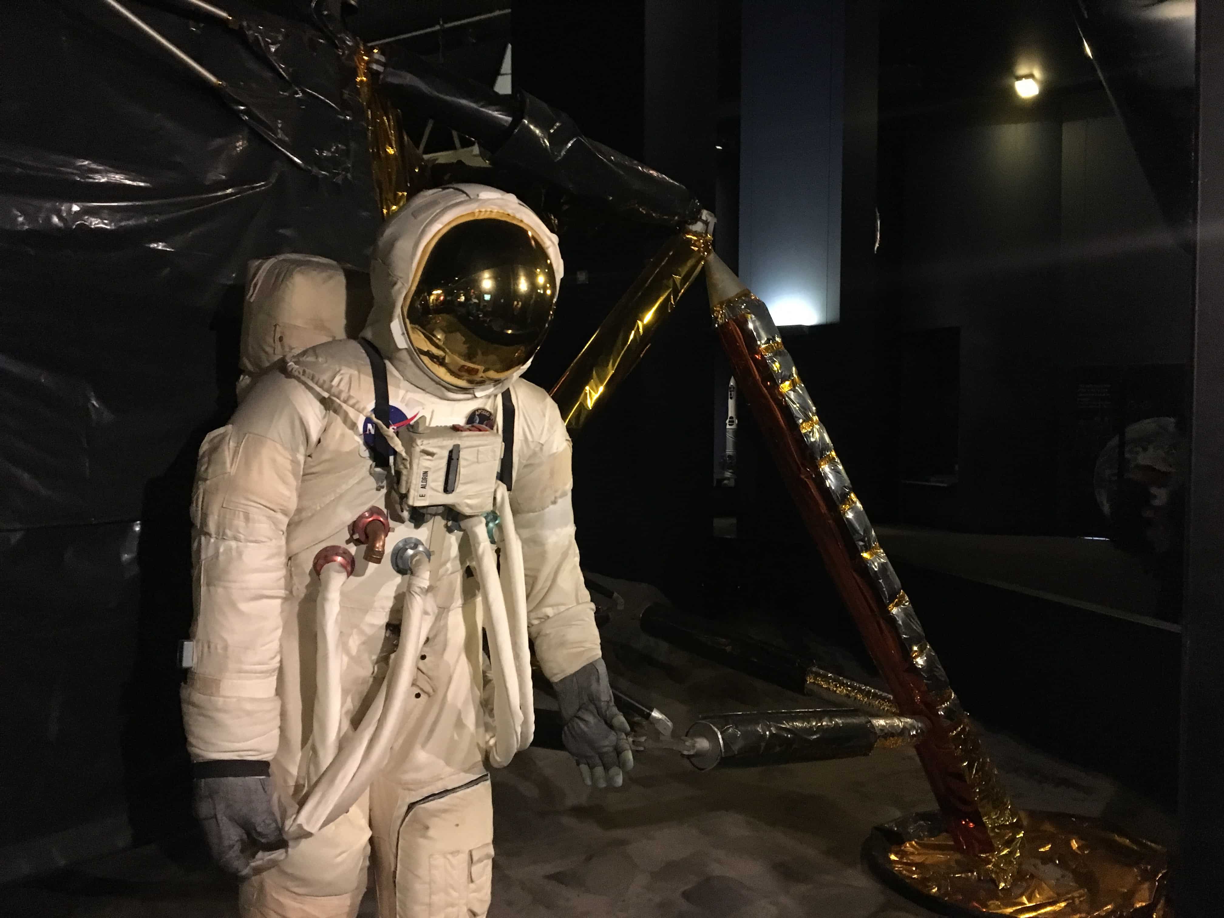 A rather stiff atronaut standing next to a tarped lunar module standing on gold foiled legs